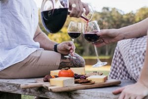 Fromart pouring wine from decanter while eating cheese
